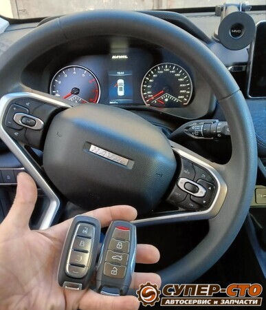 Штатный и новый смарт-ключ Haval Jolion на фоне руля и приборной панели