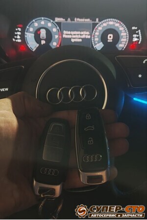 Штатный и новый смарт-ключ Audi A3 на фоне руля и приборной панели
