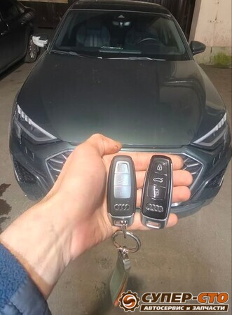 Штатный и новый смарт-ключ в руке на фоне Audi A3