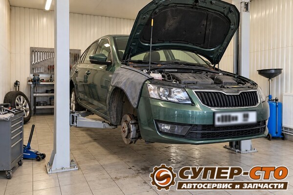Skoda Octavia на подъёмнике: капот открыт, на крыле защитная накидка, правое переднее колесо снято