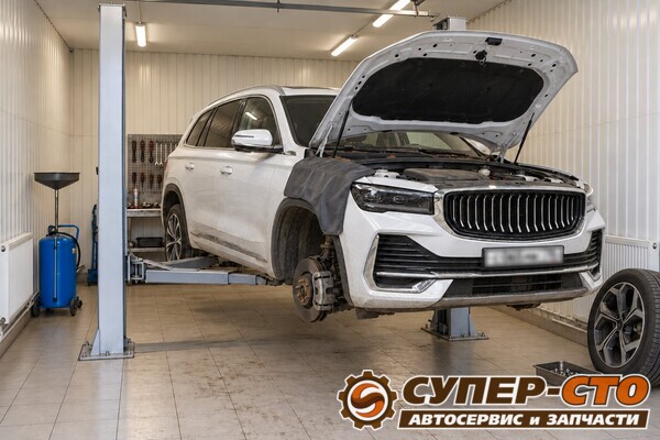 Белый Geely Monjaro на подъёмнике, капот открыт, правое переднее колесо снято