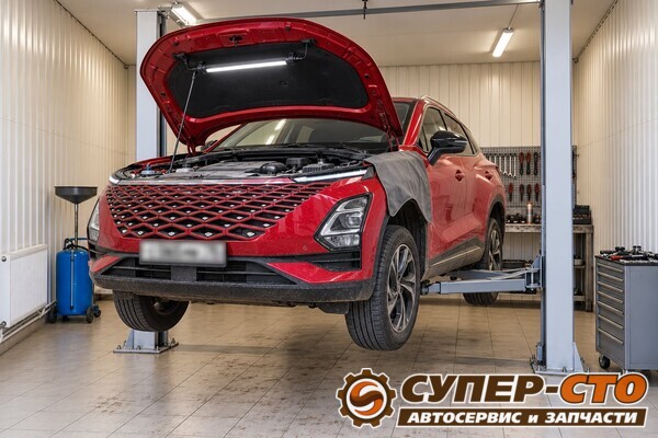 Красный Omoda C5 на подъёмнике в боксе, открыт капот